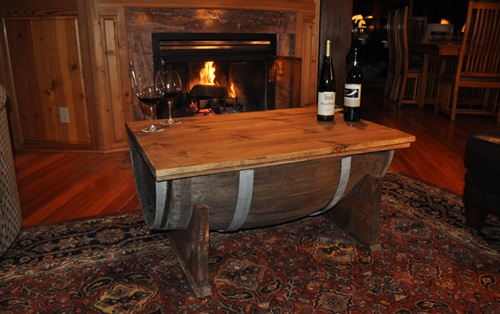 A whiskey barrel coffee table in front of a fireplace.