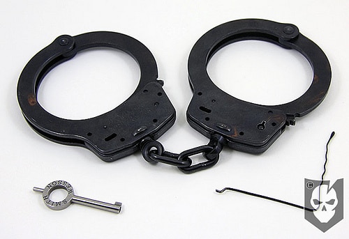 A pair of handcuffs lying on a white surface waiting for someone to pick them up.