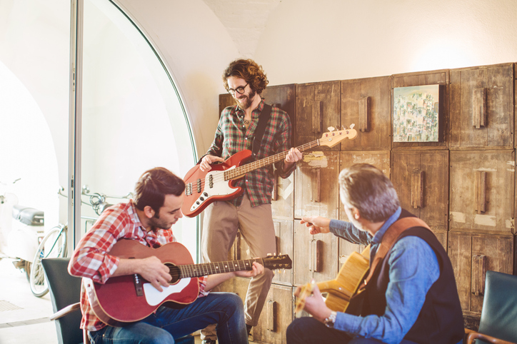 A group of men, around the same age, playing guitars in a room.