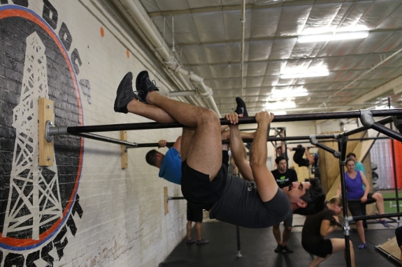 Man hanging upside down from horizontal poll.