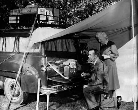 A streamline camper van standing next to a couple on a camping trip.