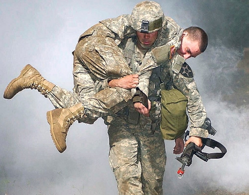 A soldier undergoes a heroic training by carrying another soldier to safety as part of the Carry a Person to Safety Workout.