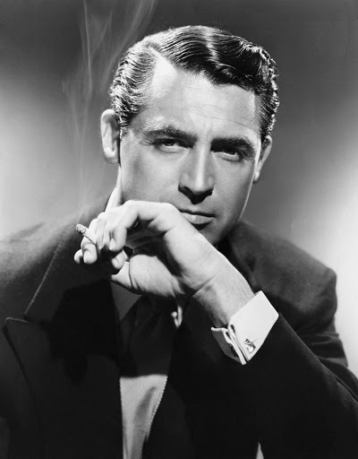 A man in a suit with Cary Grant Shine smoking a cigarette.