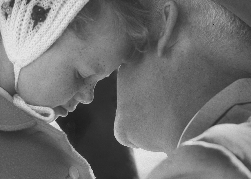 A black and white photo of an old man and a little girl captures a tender moment.