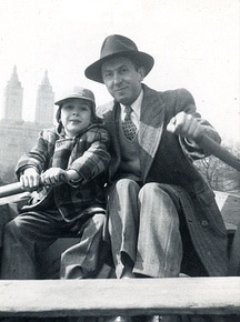 A man in a hat imparts advice to his son in a boat.