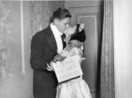 A bride and groom kissing in a hallway.