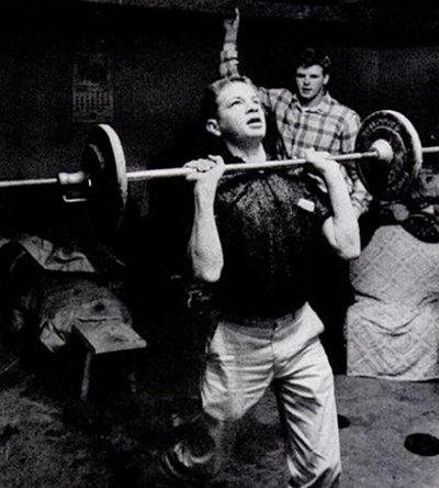 A man performing a workout with a barbell in a living room.