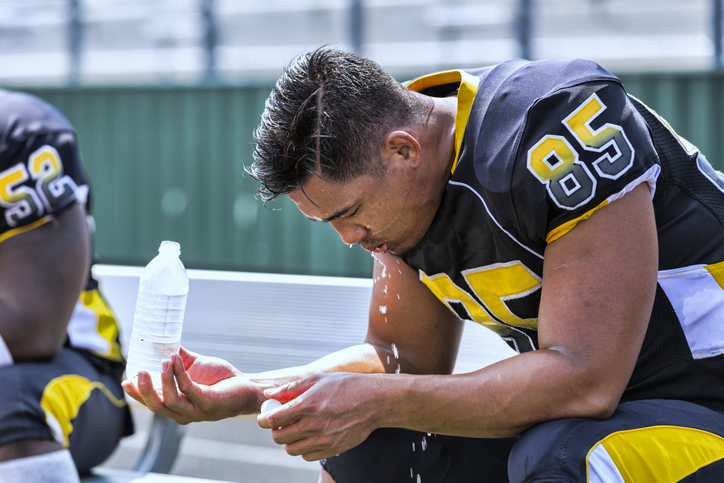 A football player resting on a bench.