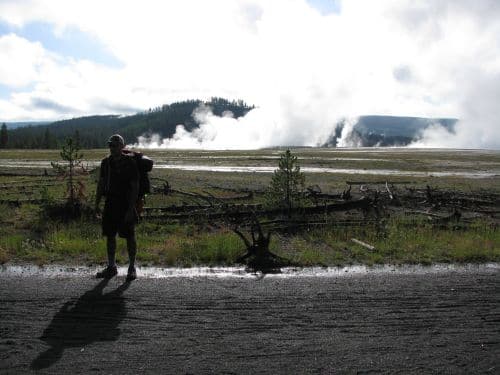 A man backpacking near a geyser.