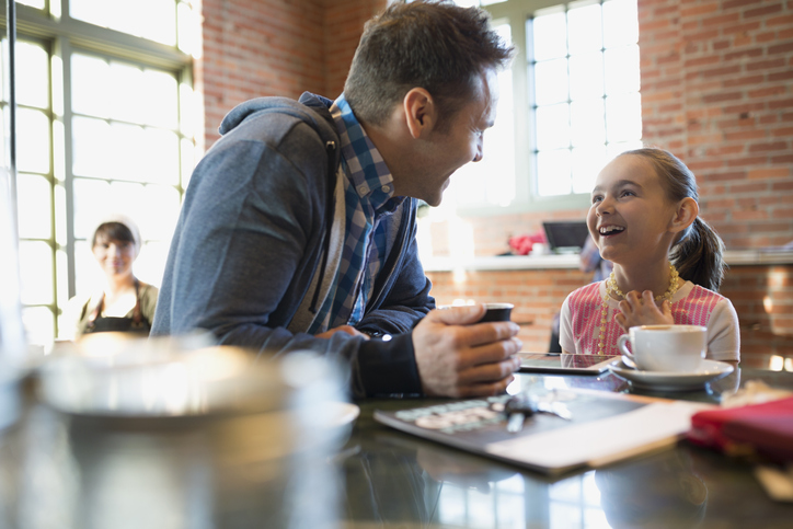 A man and a girl sitting at a table in a cafe.