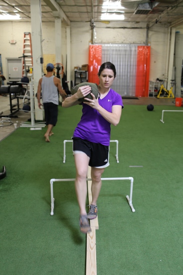 woman carrying sandbag and walking over barriers.