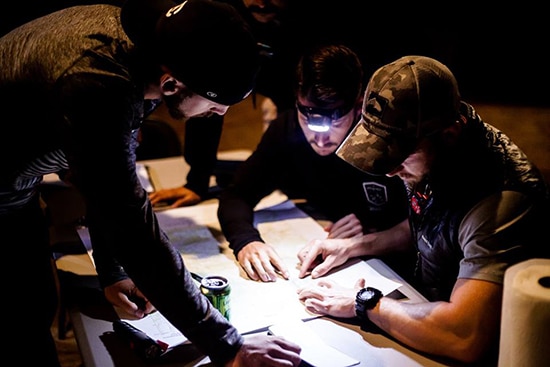 Men gathered around topographic topo Map land navigation.