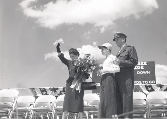 An old photo of a man and woman standing in front of a group of people, possibly from a Manvotional event.