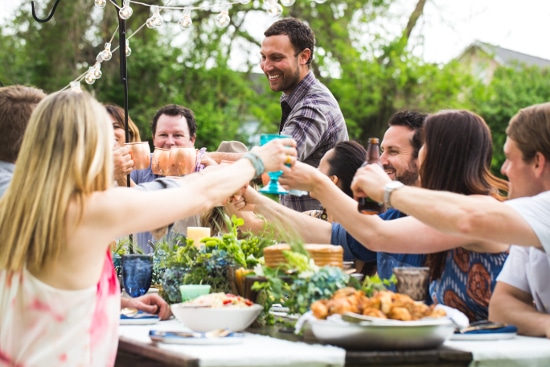 A group of people toasting at an outdoor party, celebrating with drinks in hand.