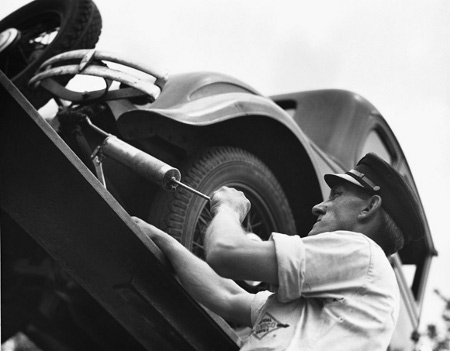 Vintage man working on car shirt sleeves rolled above elbow. 