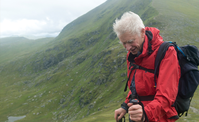 A man in a red jacket standing on top of a mountain.