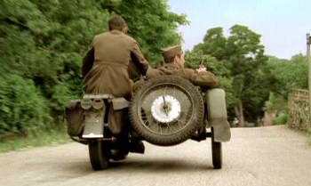 Two men riding a motorcycle down a country road on Veterans Day.