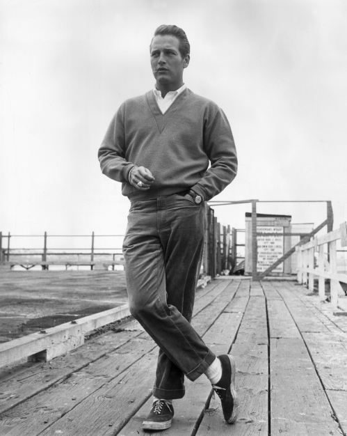 A man in a sweater and khakis standing on a dock.