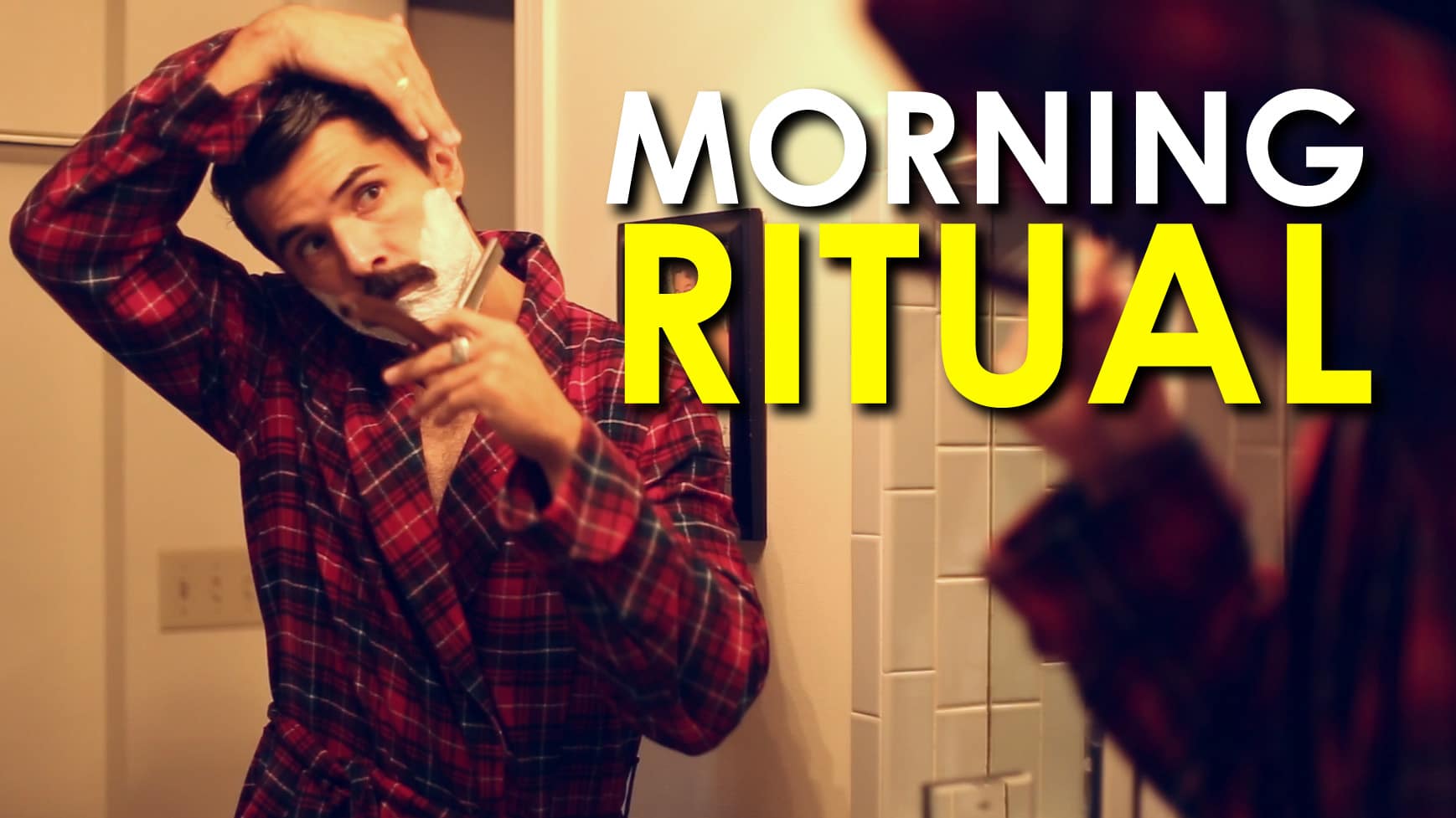 A man is shaving in front of a mirror as part of his morning routine.