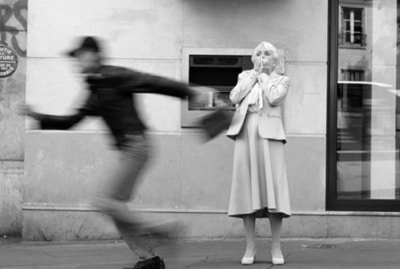 A black and white photo featuring a woman engaged in a chase down the street.