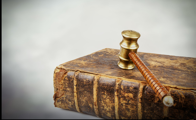 An old book with a gavel on top of it, symbolizing the rules of the universe.