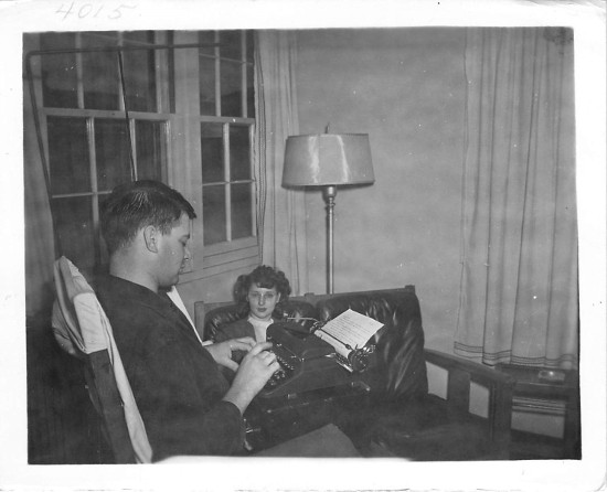 An old black and white photo of a man and woman sitting in a chair.