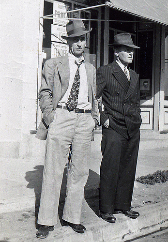 Two men with hats standing in front of an ugly mug store.