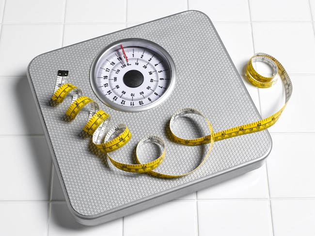 Analog bathroom scale with a measuring tape on top for men looking to lose weight.