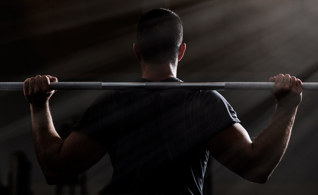 A man lifting a barbell on a bench in the gym, showcasing his strength.