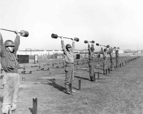 A group of men in a Strength Course doing squats with barbells during WWII Workout Week.