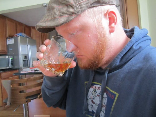 A man sniffing whiskey in glass.