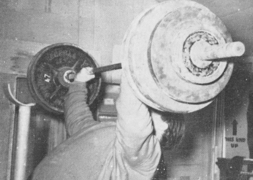 A man is working out with a barbell in the gym.