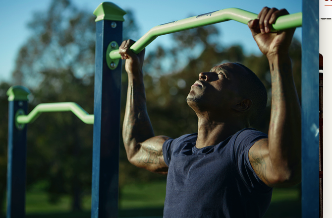 A man is performing pull-ups on a bar as part of his strength training routine.